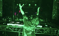 a dj with his hands raised in the air at a concert